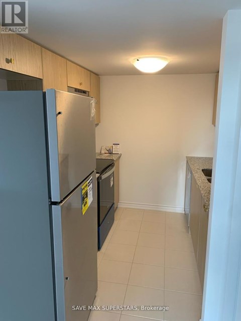 A kitchen with a refrigerator and a stove top oven.