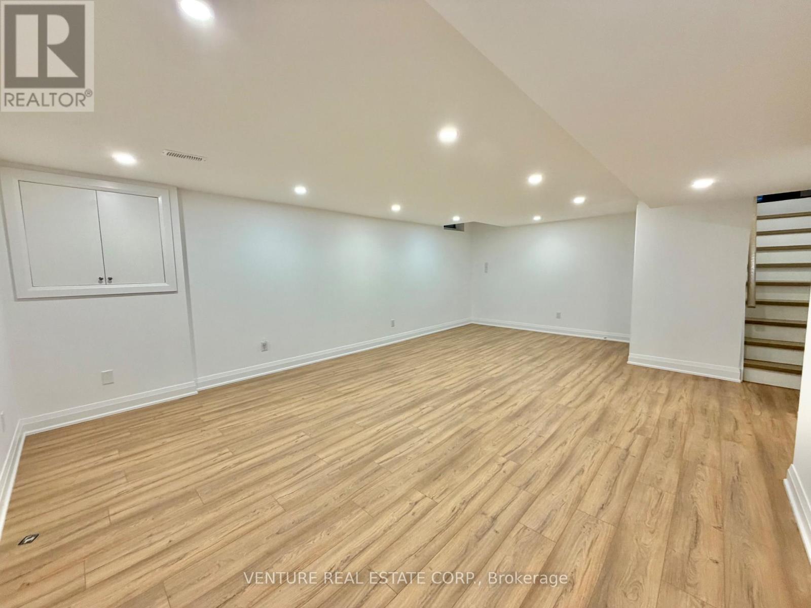 A spacious room with wooden flooring and white walls.