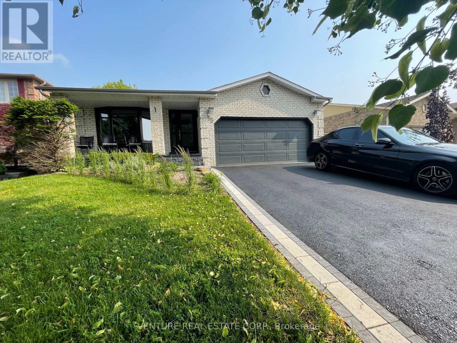 A black car is parked in front of a house with a garage.