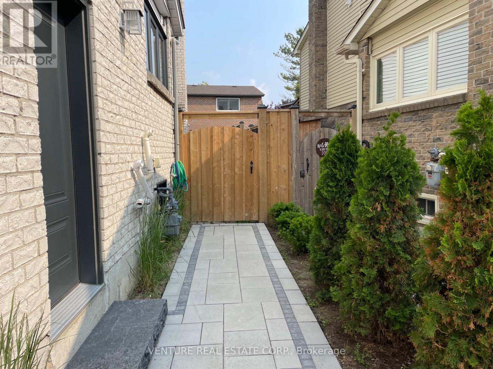 A brick house with a wooden gate and a stone pathway leading to it.