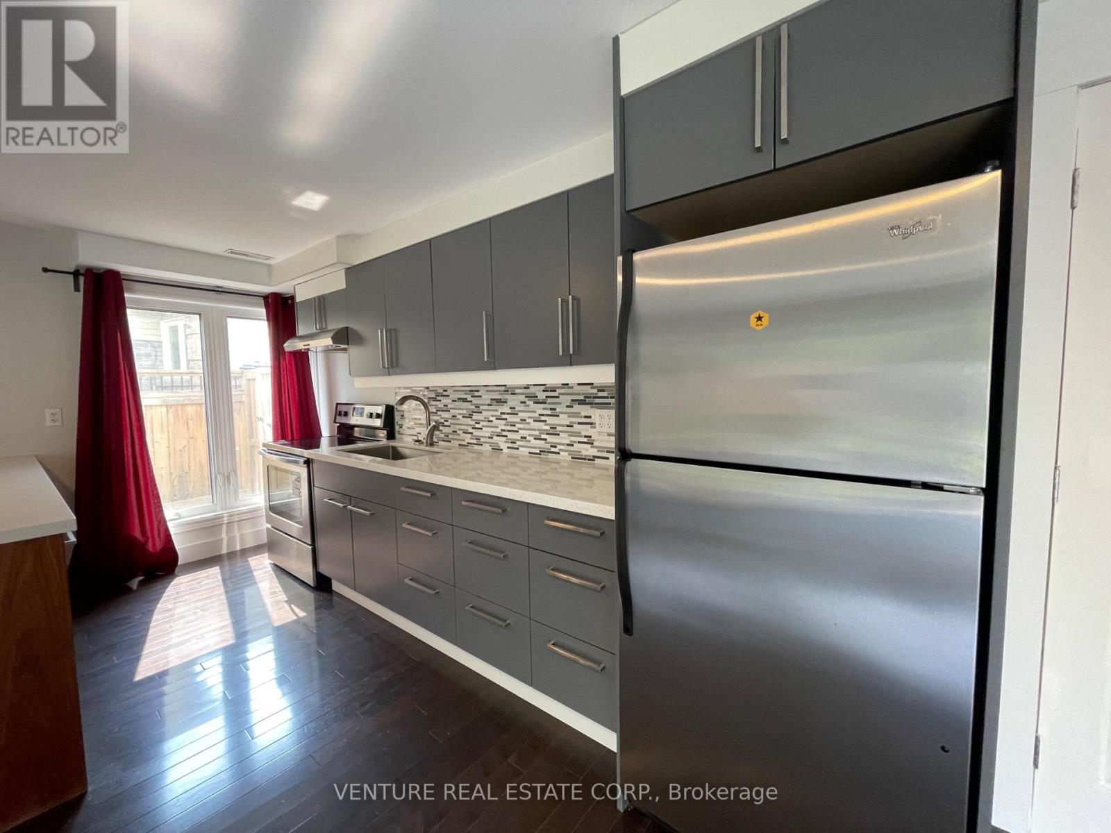 A kitchen with a stainless steel refrigerator and a countertop with a sink.