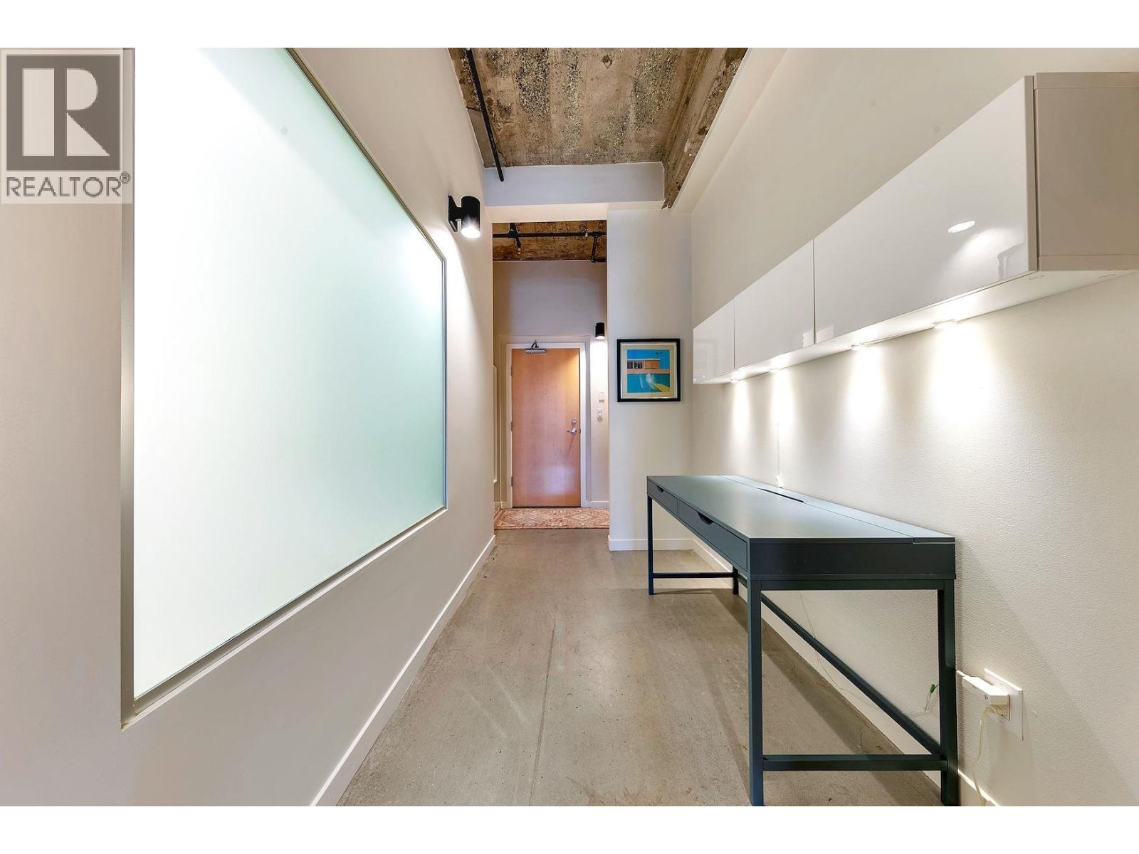 A long black table is in a white room with a door in the background.
