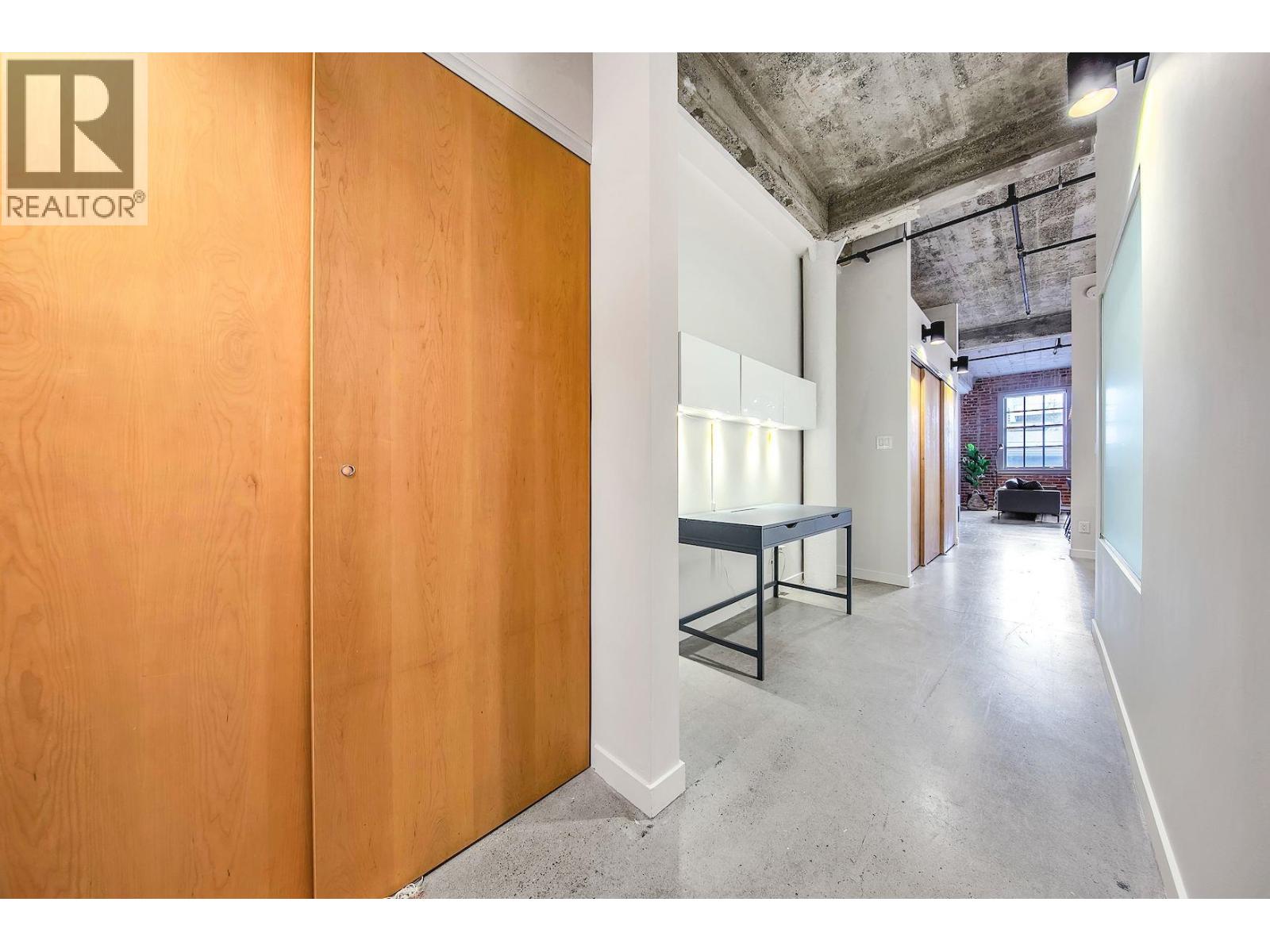 A room with a wooden door and a table in the middle.