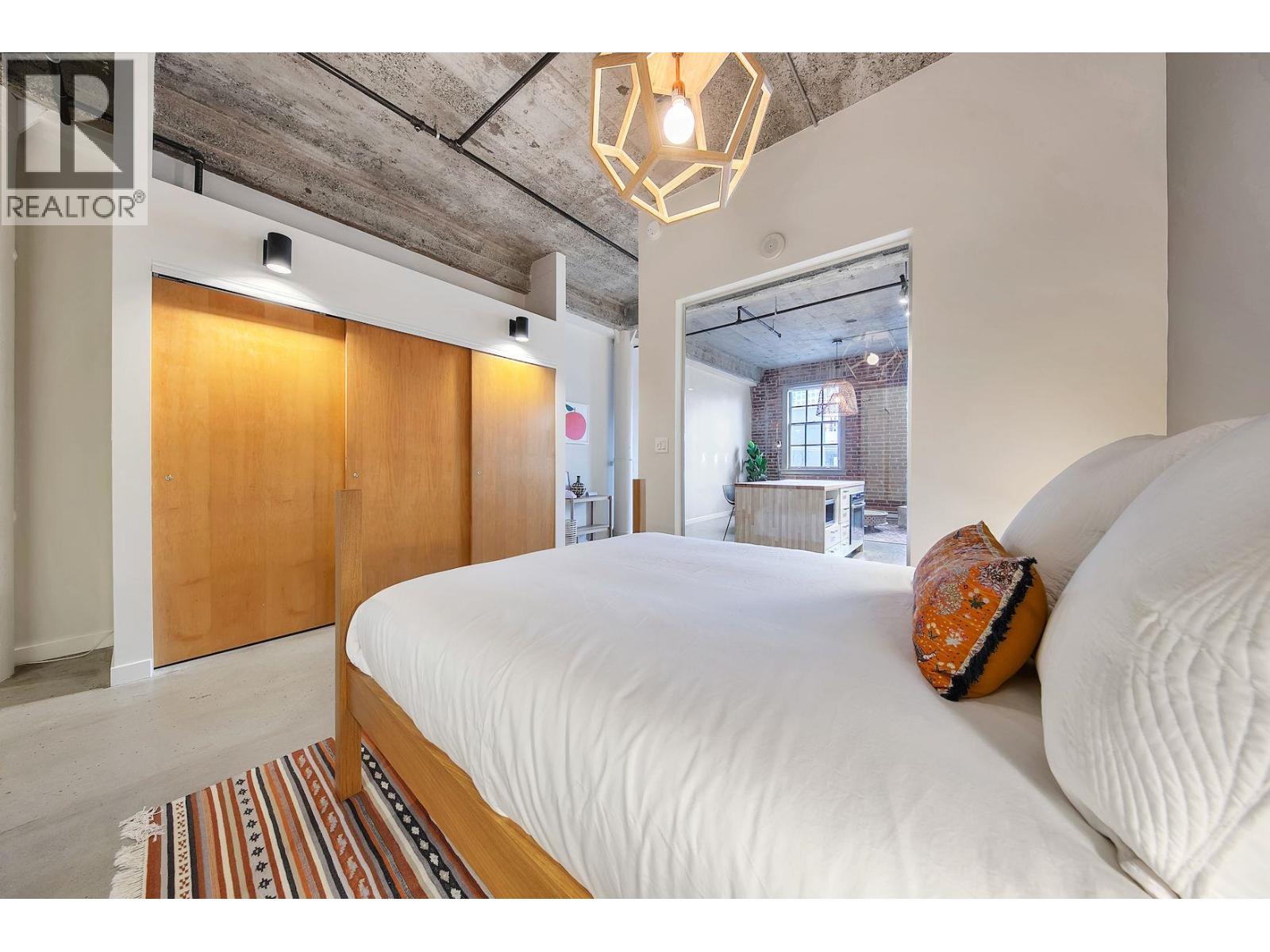 A bedroom with a bed, pillow, and a rug in front of a wooden door.