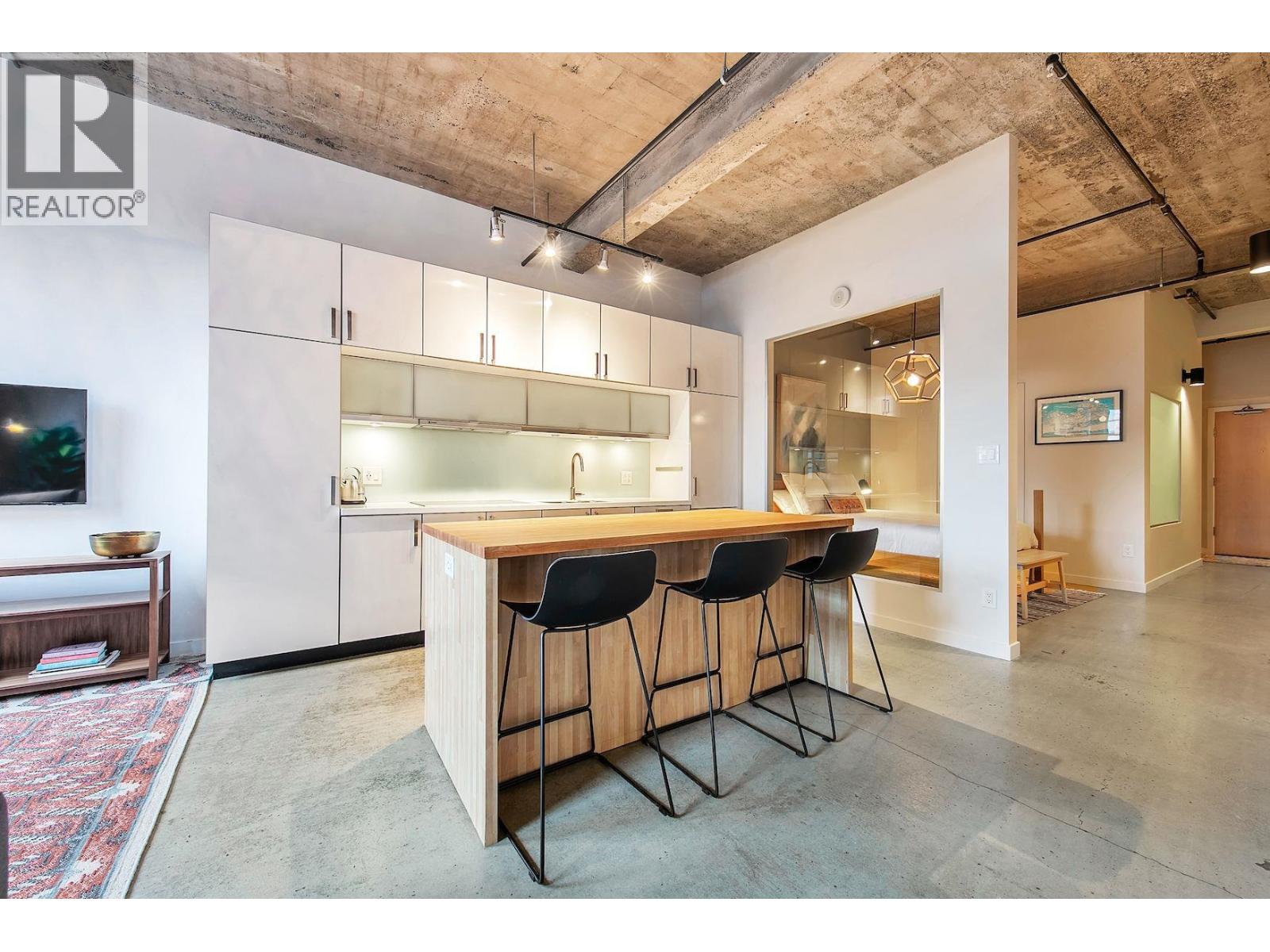 A modern kitchen with a bar area and a television.