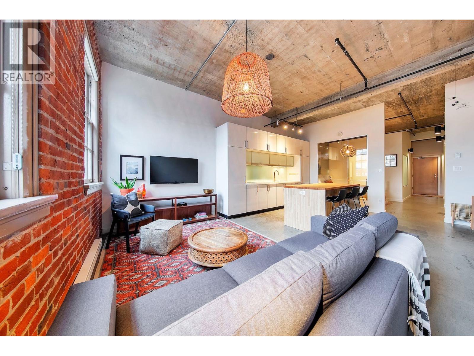 A living room with a grey sofa and a red rug.