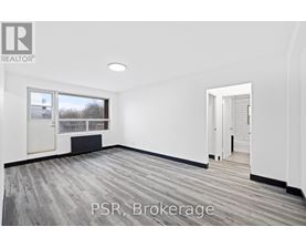 A room with a large window and a door leading to another room.