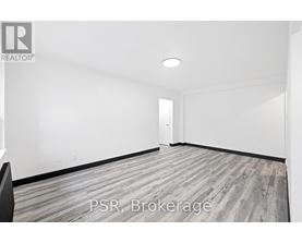 A room with a wooden floor and white walls, with a door in the background.