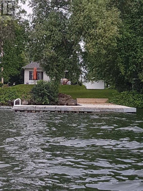 A house is situated by a body of water with a dock leading to it.