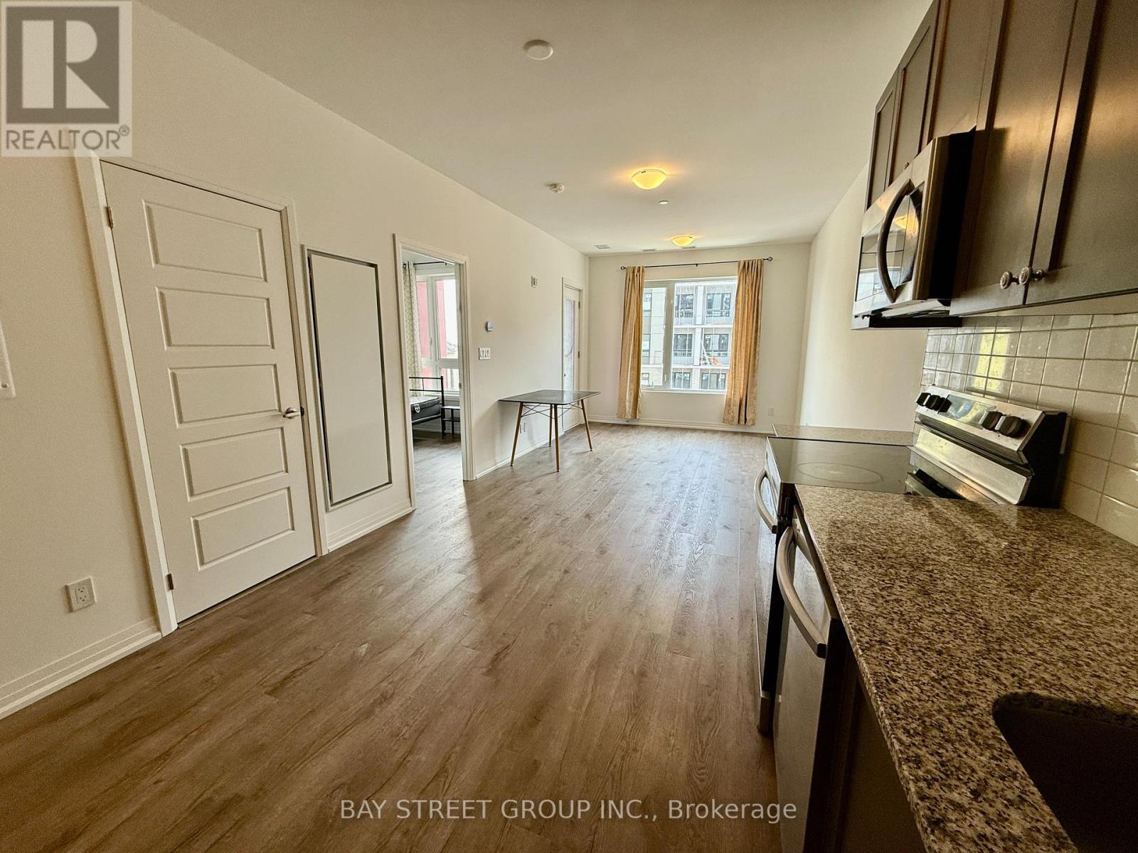 A kitchen with wooden floors and a countertop with a microwave and oven.