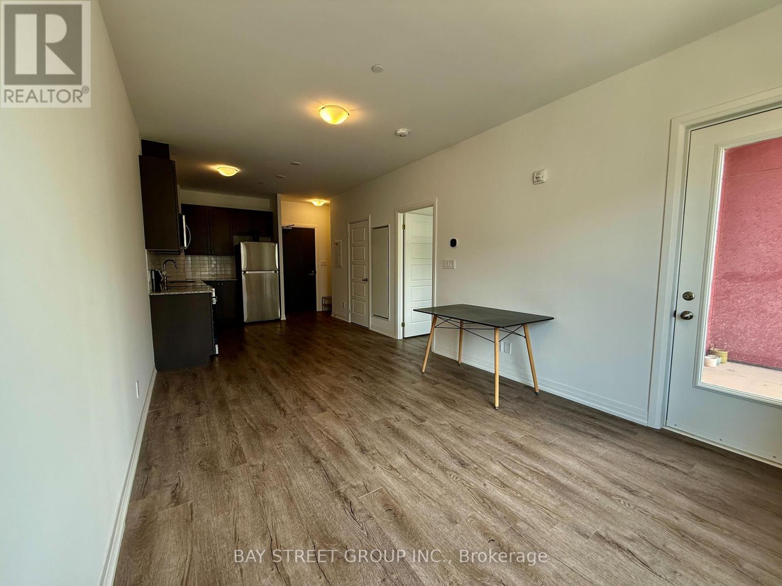 A spacious room with a table and chairs in the foreground and a kitchen area in the background.