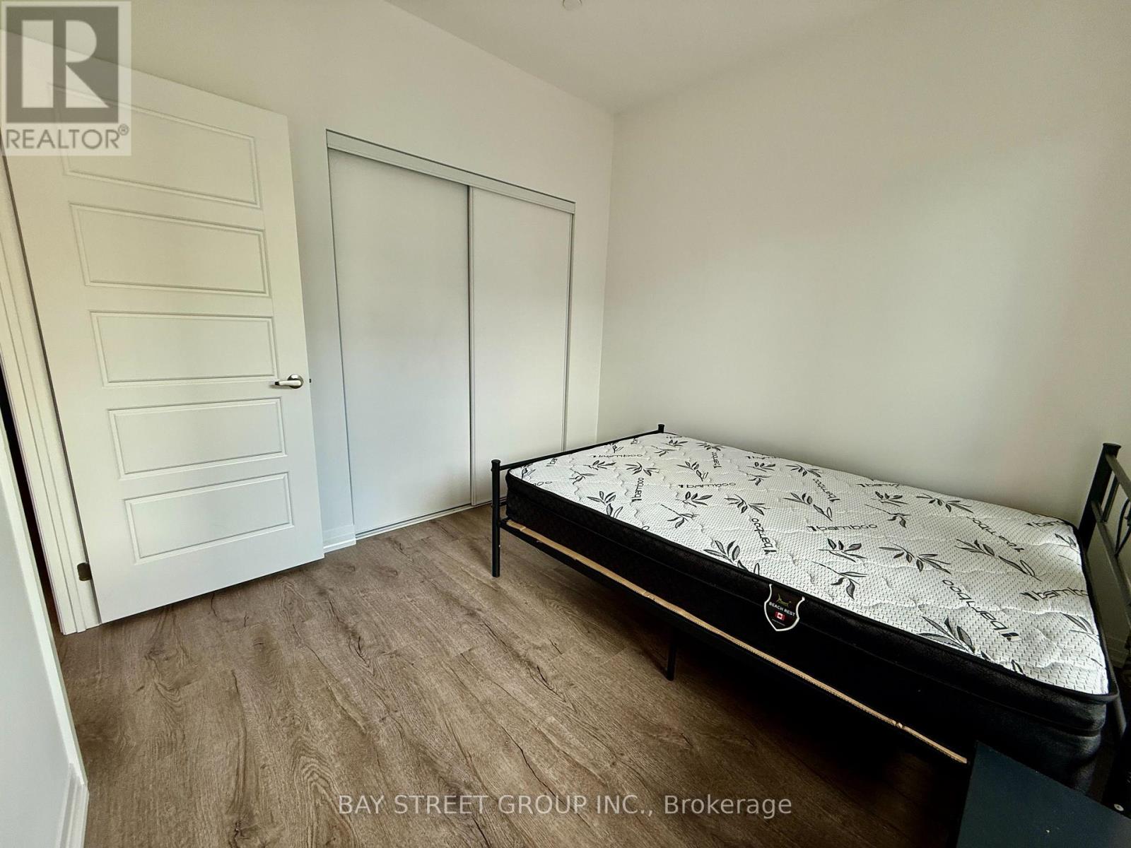 A bedroom with a bed, dresser, and two doors.
