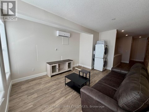 A living room with a brown leather couch and a white refrigerator.
