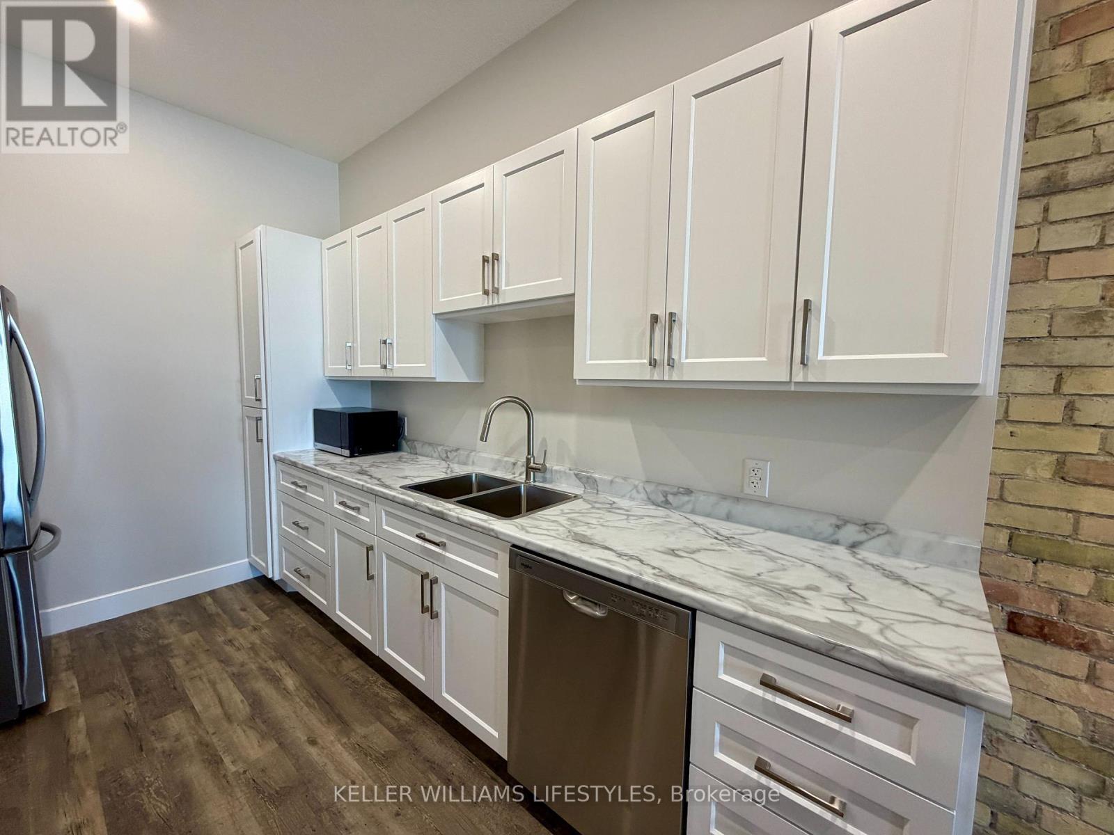 A kitchen with white cabinets and a marble countertop.