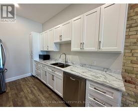 A kitchen with white cabinets and a marble countertop.