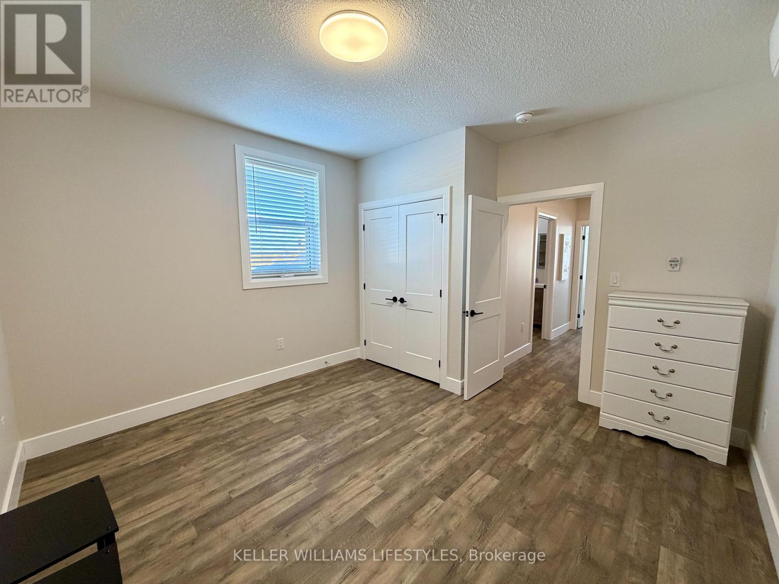 A bedroom with a wooden floor and a white dresser.