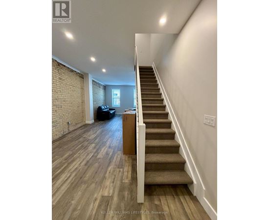A staircase with wooden steps and a white railing leads to a living room with a couch and a coffee table.