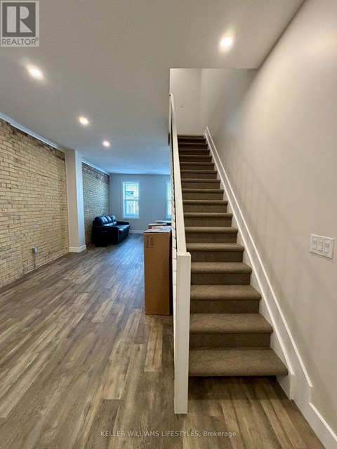 A staircase with wooden steps and a white railing leads to a living room with a couch and a coffee table.