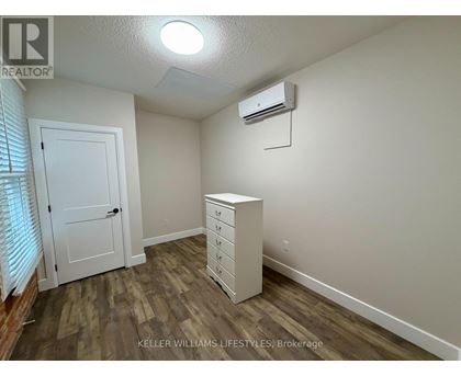 A bedroom with a white dresser and a window with blinds.