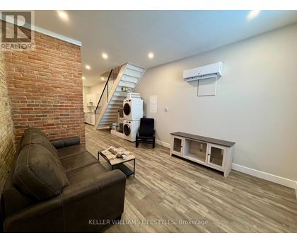 A living room with a brown leather couch and a brick wall.