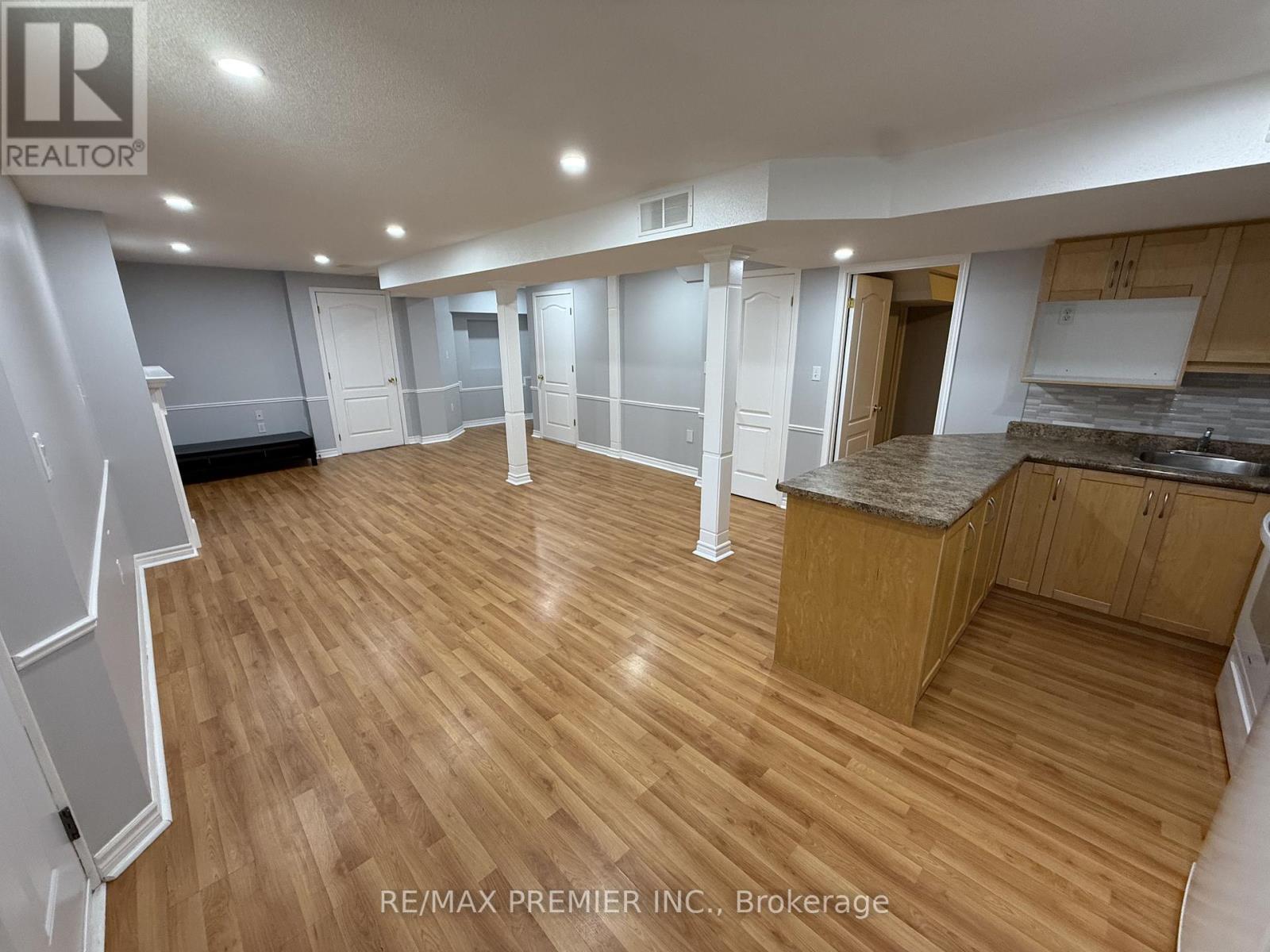 A spacious room with wooden flooring and white walls.