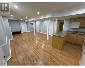 A spacious room with wooden flooring and white walls.