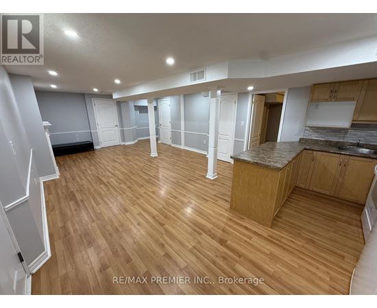 A spacious room with wooden flooring and white walls.