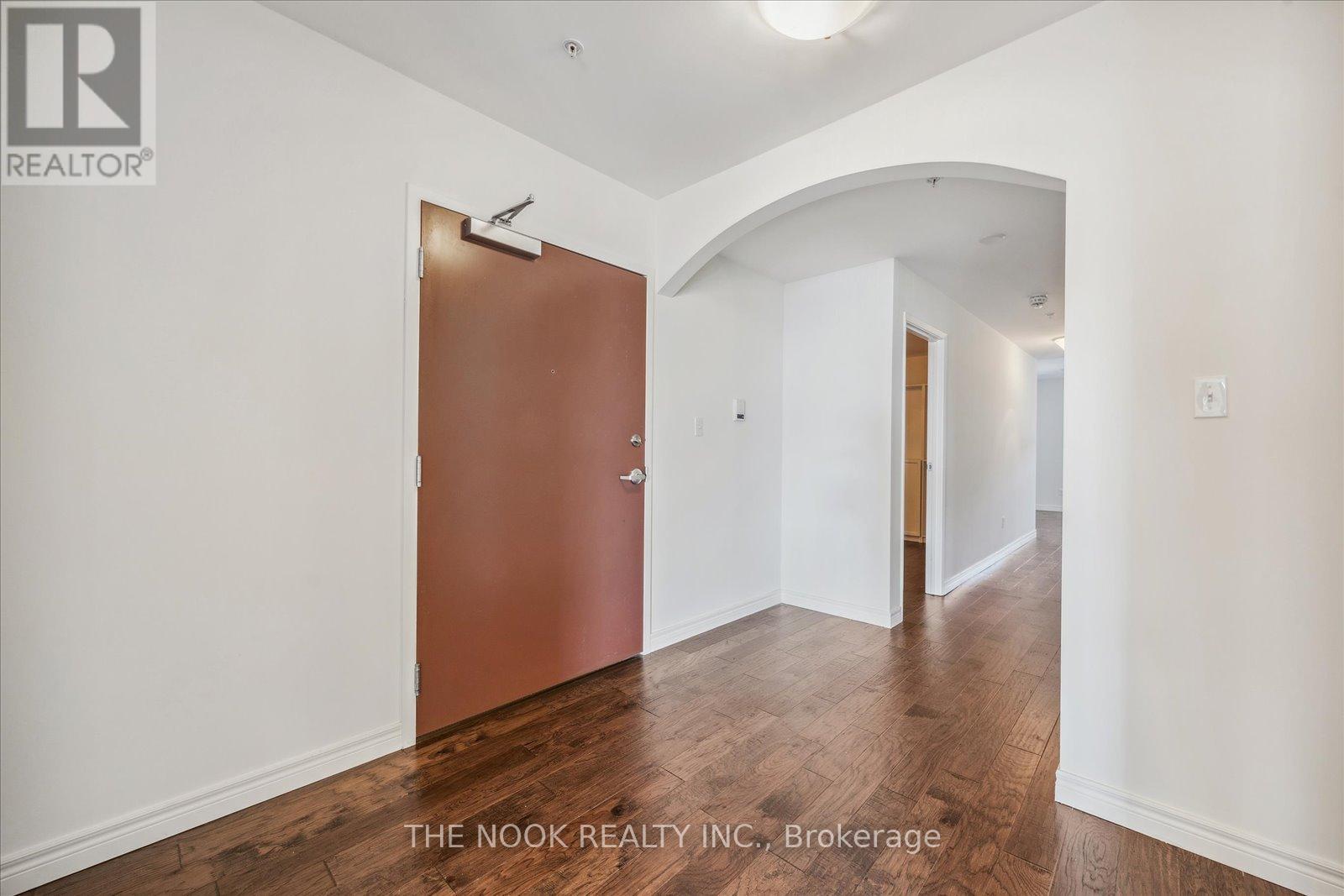 A hallway with a brown door and white walls.