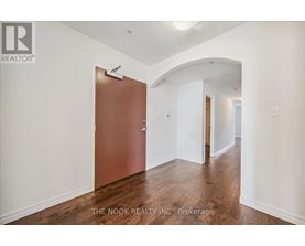 A hallway with a brown door and white walls.