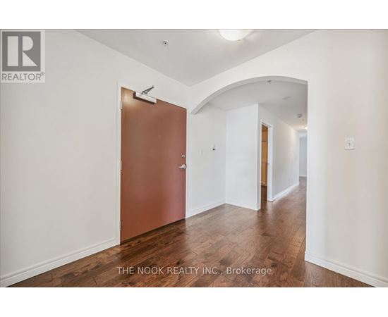 A hallway with a brown door and white walls.