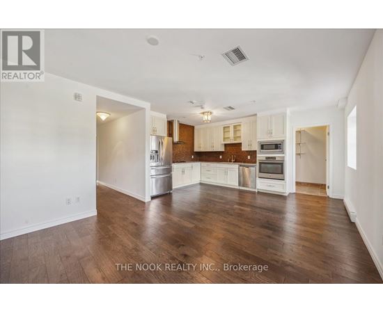 A spacious kitchen with white cabinets and wooden floors.