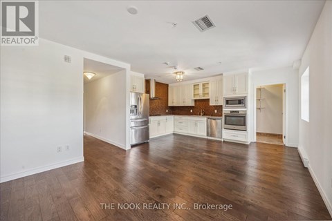 A spacious kitchen with white cabinets and wooden floors.