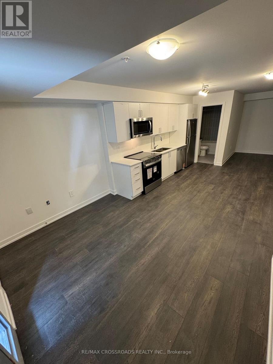 A spacious room with a kitchenette and wood flooring.