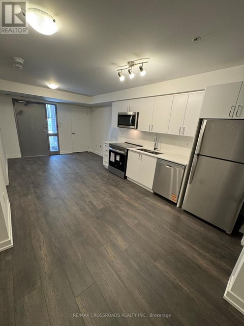 A kitchen with white cabinets and a grey floor.