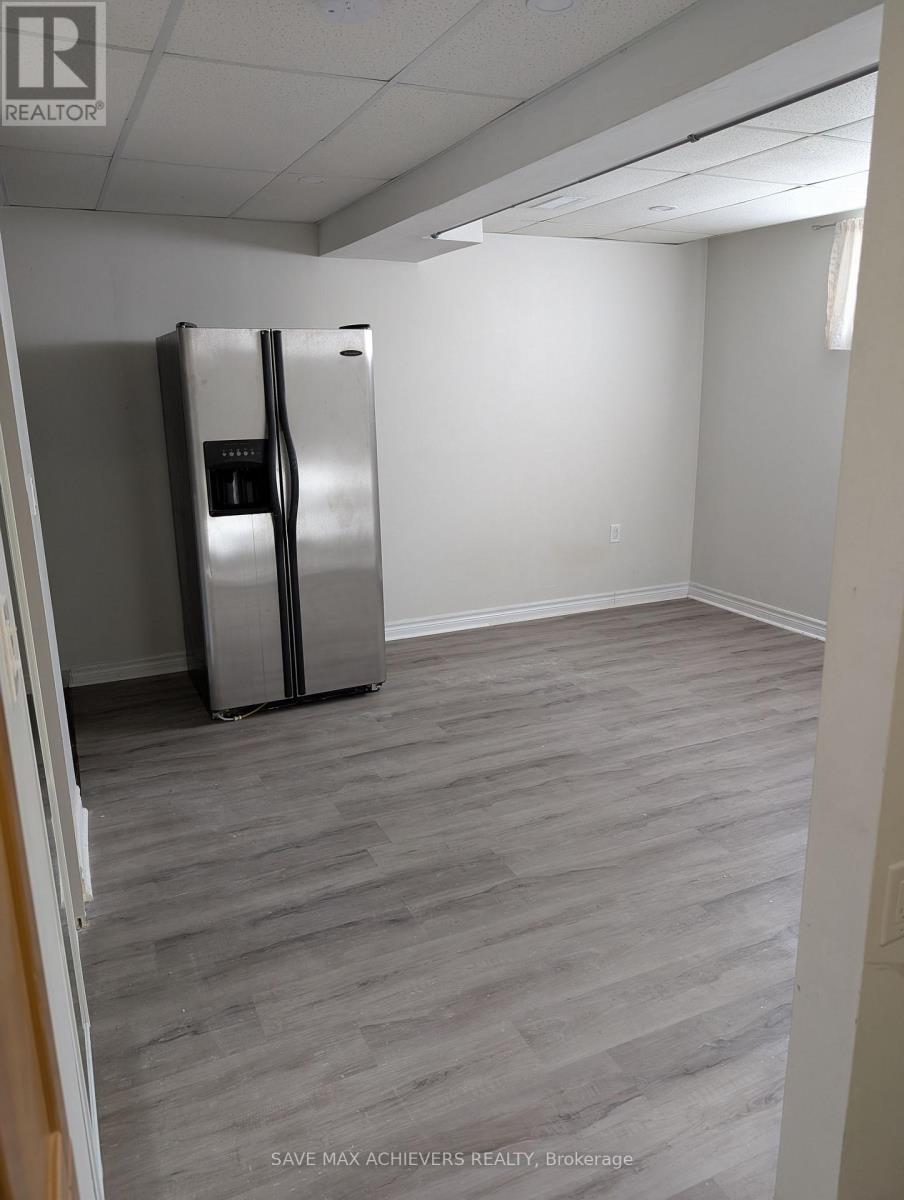 A room with a fridge and wood flooring.