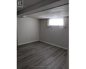 A room with wooden flooring and a window with curtains.