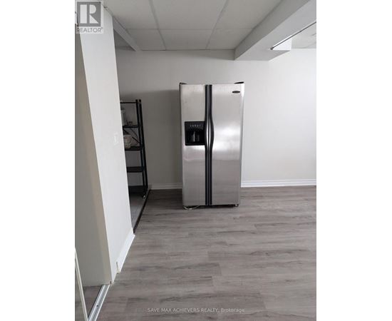 A stainless steel refrigerator in a room with wooden flooring.