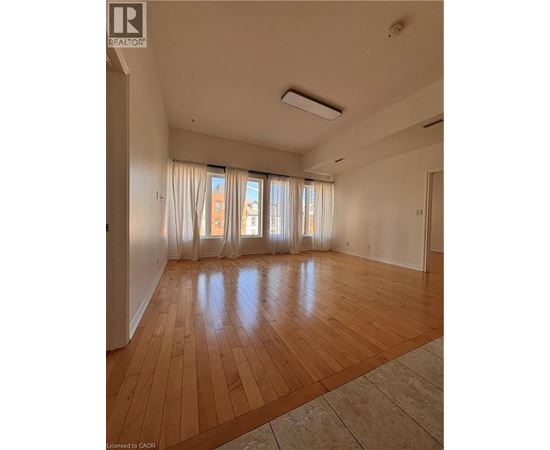 A room with a window overlooking a street with apartment buildings.