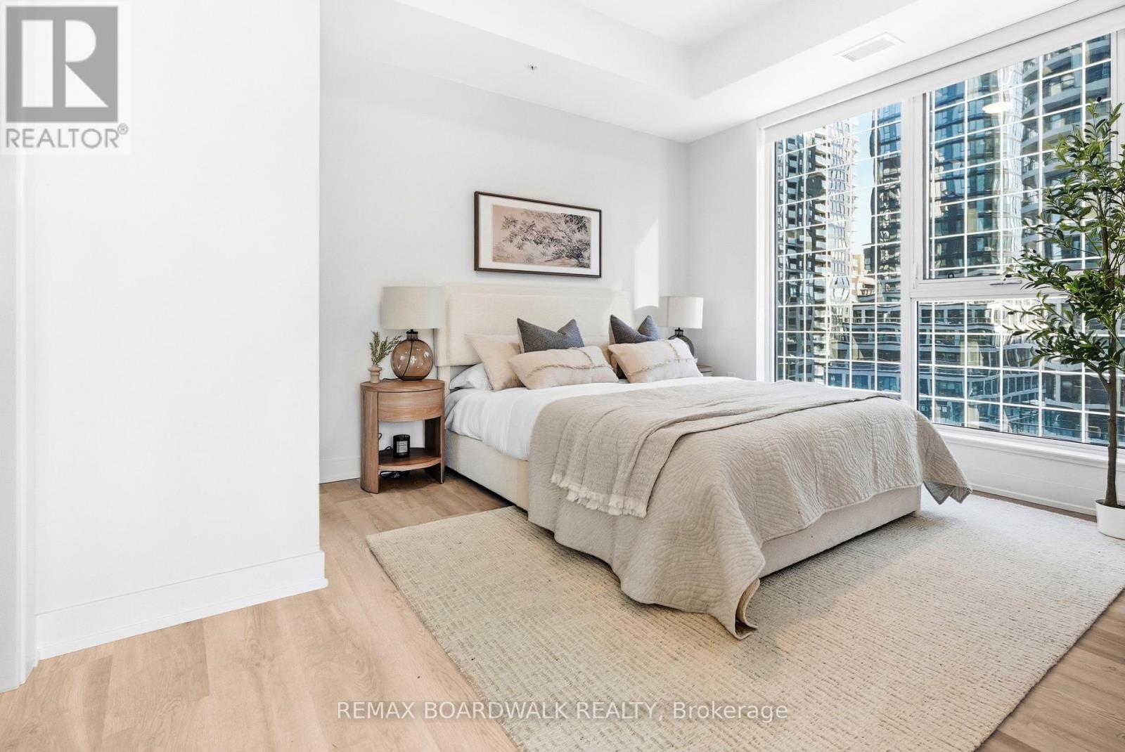 A bedroom with a large bed and a window overlooking a cityscape.