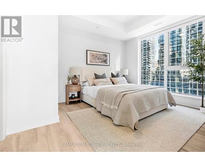 A bedroom with a large bed and a window overlooking a cityscape.