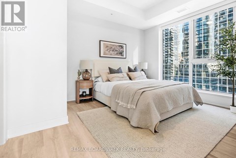 A bedroom with a large bed and a window overlooking a cityscape.