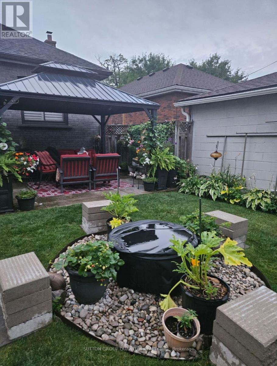 A backyard with a BBQ grill surrounded by potted plants and a patio area.