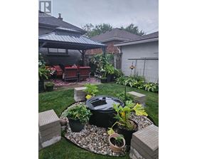 A backyard with a BBQ grill surrounded by potted plants and a patio area.