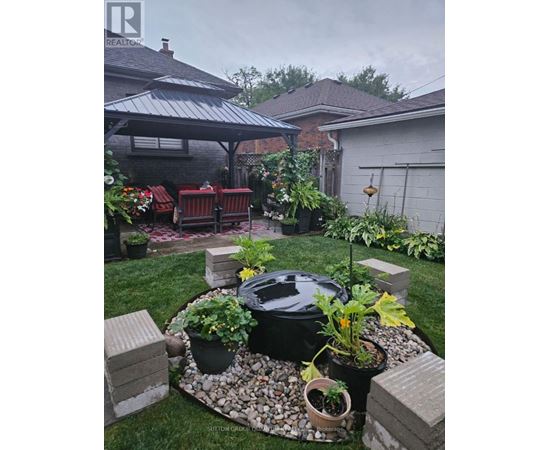 A backyard with a BBQ grill surrounded by potted plants and a patio area.