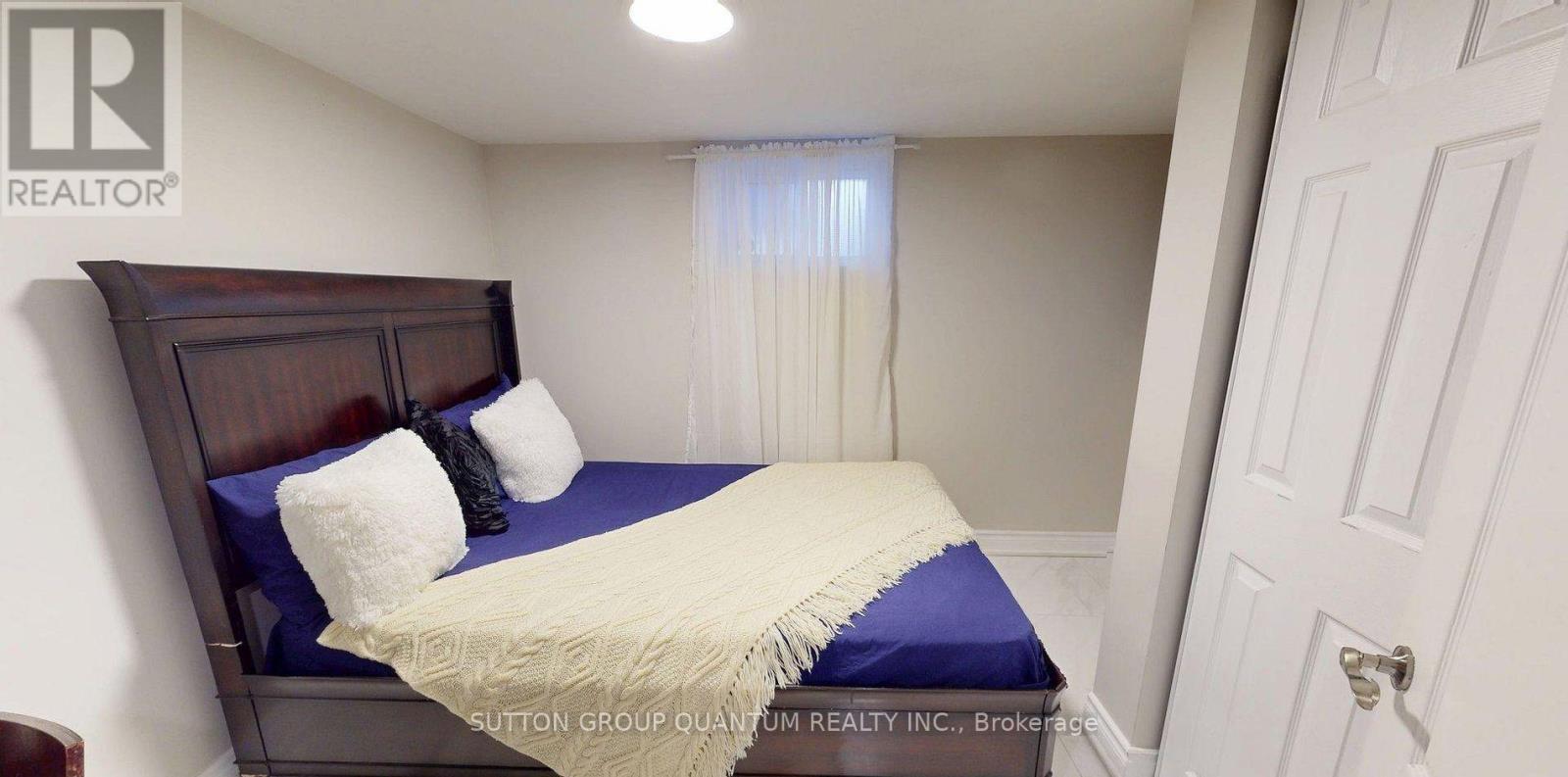 A bedroom with a bed, pillows, and a window with curtains.