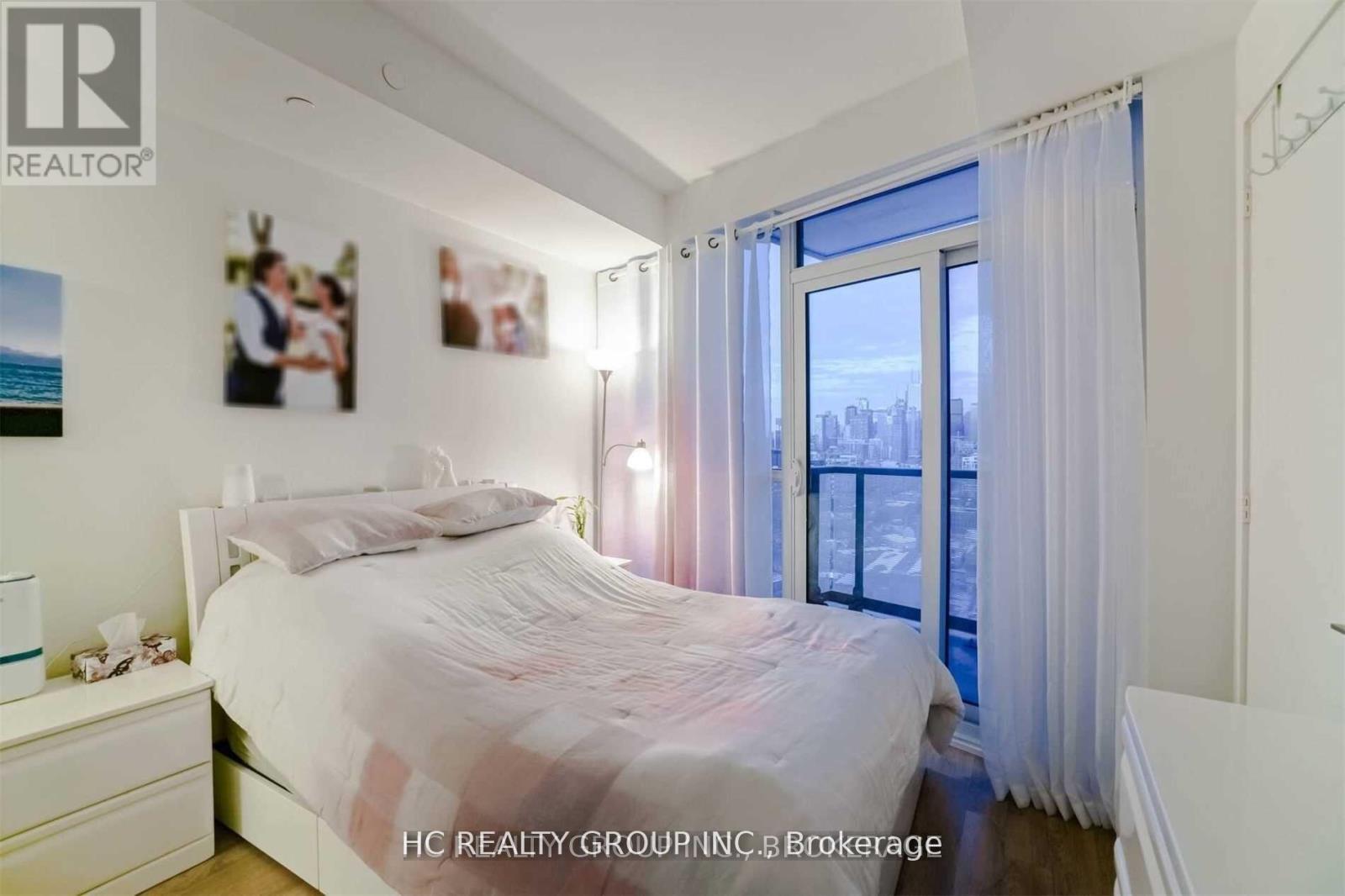 A bedroom with a large bed and a window overlooking a cityscape.