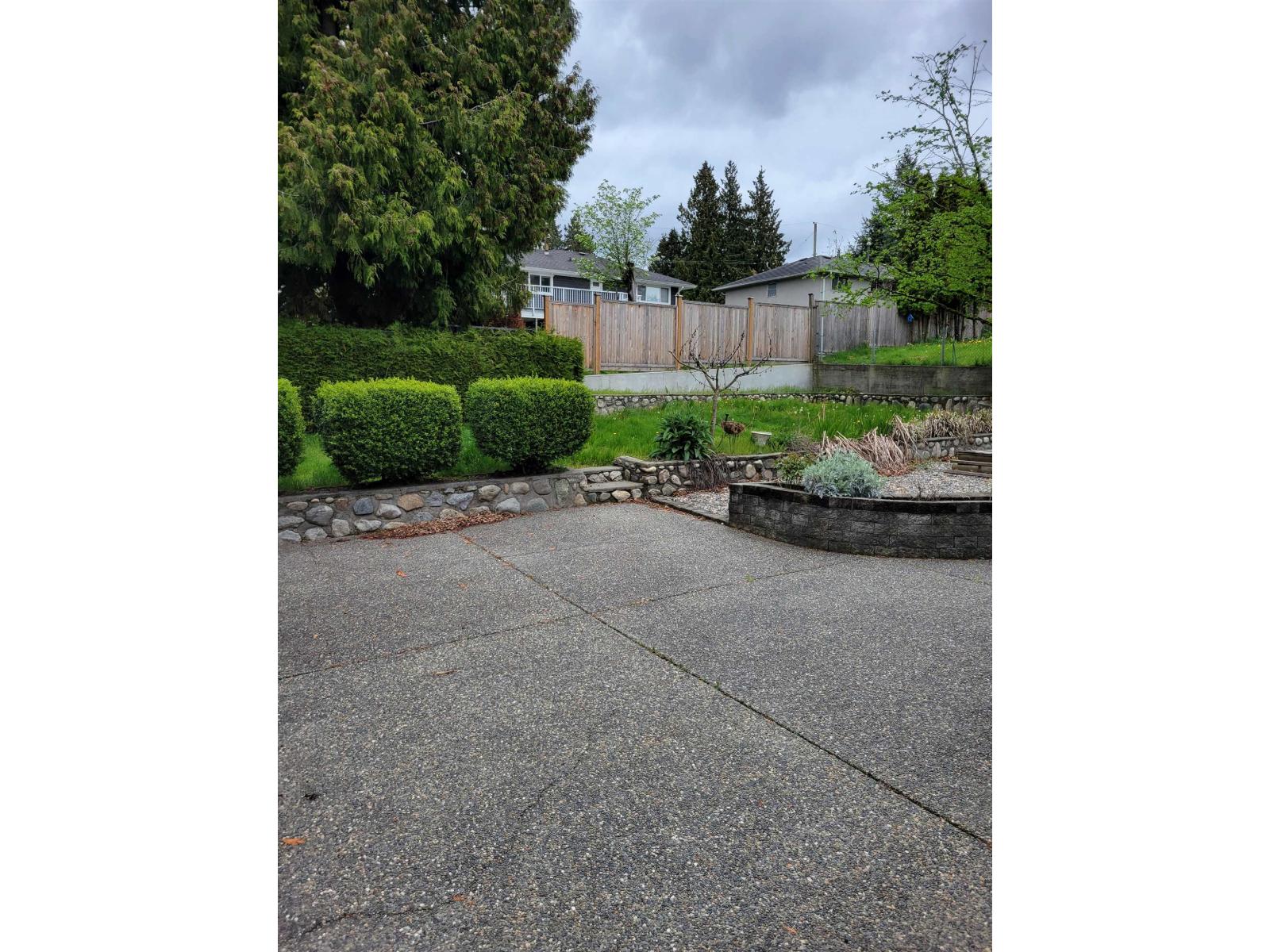 A concrete patio with a small garden in front of a house.