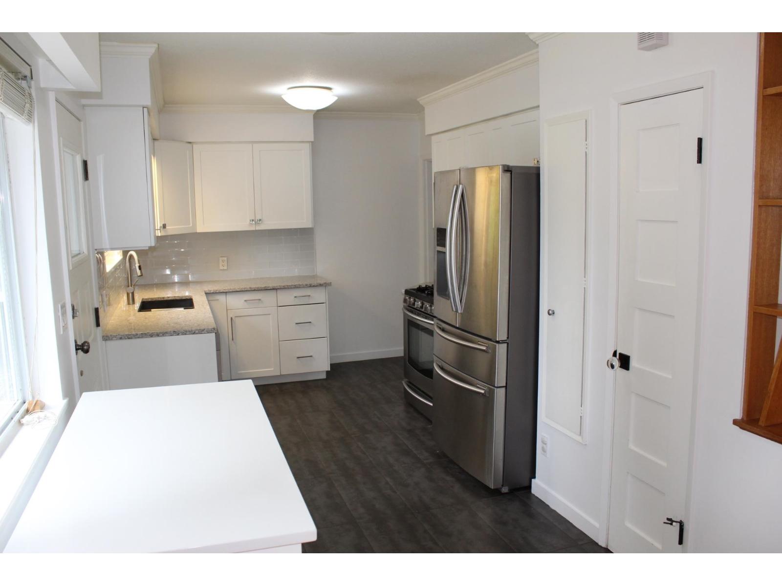 A kitchen with white cabinets and a stainless steel refrigerator.