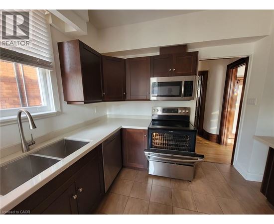 A kitchen with brown cabinets and a stainless steel oven.