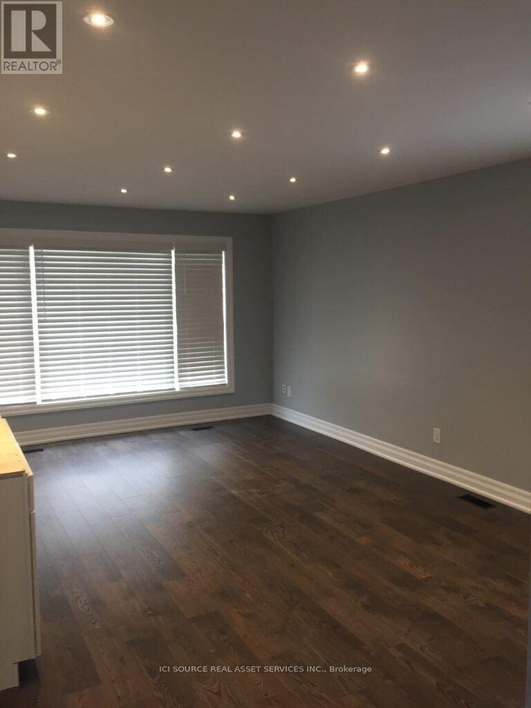 A room with wooden flooring and a window with blinds.